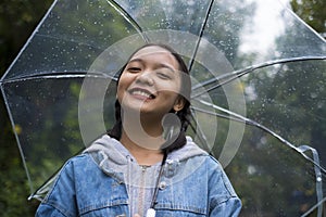 Happy young girl playing with rain in green garden