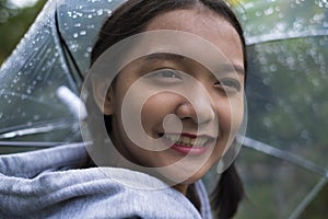 Happy young girl playing with rain in green garden