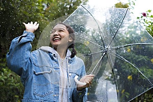 Happy young girl playing with rain in green garden