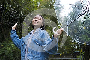 Happy young girl playing with rain in green garden