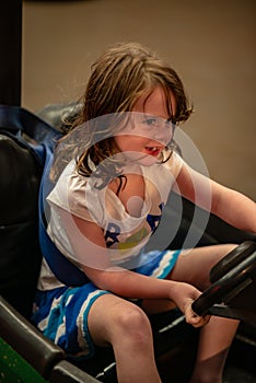 Happy young girl rides electric bumper car amusement ride on shore boardwalk