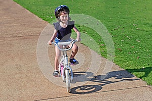 Happy young girl riding a bike in the park