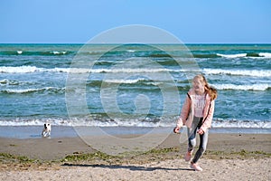 Happy young girl run with dog on beach.