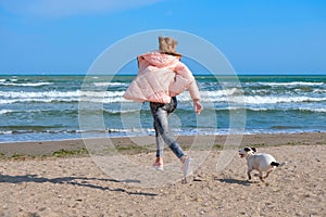 Happy young girl run with dog on beach.