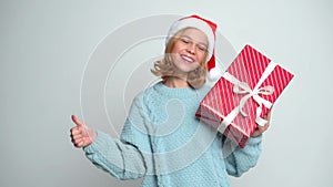 Happy Young girl in Santa Claus cap holding present