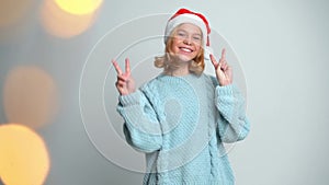 Happy Young girl in Santa Claus cap show peace by fingers