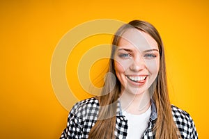 Happy young girl in shirt smiling and laughing showing white teeth and standing on yellow background photo