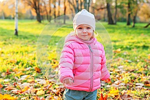 Happy young girl smiling in beautiful autumn park on nature walks outdoors. Little child playing in autumn fall orange