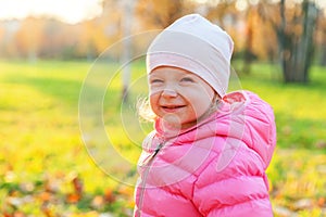Happy young girl smiling in beautiful autumn park on nature walks outdoors. Little child playing in autumn fall orange yellow