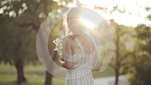 Happy young girl sniffing flowers, enjoying nature and smiling. Portrait of woman in front of sunlight spending weekend