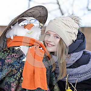 Happy young girl with a snowman, close up