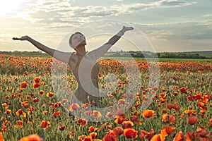 Happy young girl standing in the poppies field