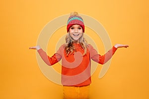 Happy Young girl in sweater and hat shrugs her shoulders