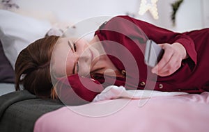 Happy young girl using smartphone on bed, online dating concept.