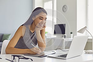 Happy young girl working on design project using modern graphic tablet and laptop computer