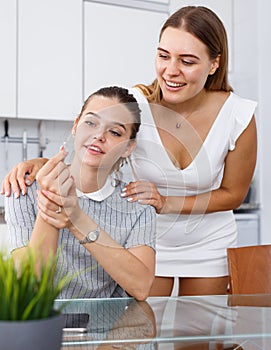 Happy young girlfriends looking betrothal ring and chatting at table