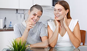 Happy young girlfriends looking betrothal ring and chatting at table