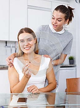 Happy young girlfriends looking betrothal ring and chatting at table