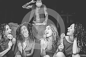 Happy young girls eating candy lollipop at party in night disco club - Millennials women having fun together - Youth, generation