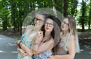 Three beautiful young boho chic stylish girls walking in park.