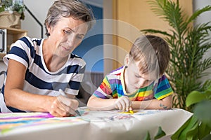 Happy young grandmother draw art picture playing grandson enjoy family weekend