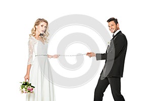 happy young groom with chain and leashed bride