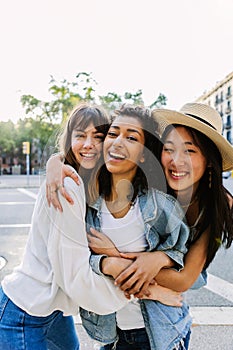 Happy young group of diverse female friends laughing together at city street