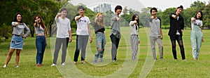 Happy young group of friends pointing at camera together at the park