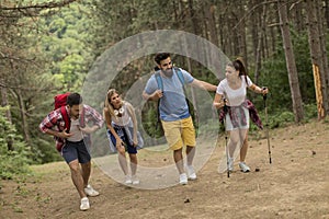 Happy young group hiking together through the forest