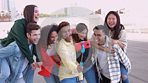 Happy young group of multiracial friends taking self portrait with selfie stick