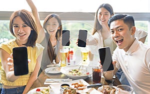 Happy young group Showing mobile phone with blank screen in restaurant