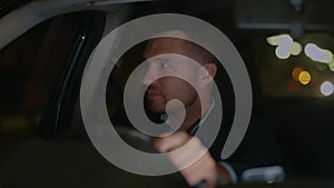 Happy young guy enjoying his trip while driving car at night, holding the steering wheel with hands. Right hand drive