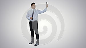 Happy young handsome businessman recording vlog or making video call on gradient background.