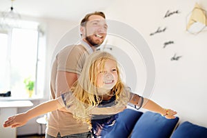 Happy young handsome father with his little curly hair daughter playing at home