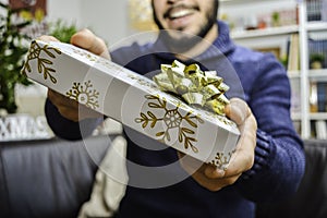 Happy young handsome man holding and giving a gift to someone