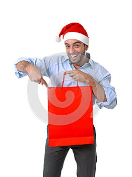 Happy young handsome man wearing santa hat holding red shopping bag