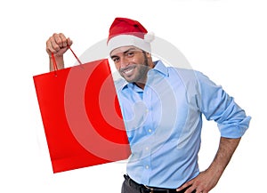 Happy young handsome man wearing santa hat holding red shopping bag