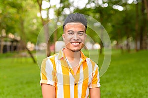 Happy young handsome multi ethnic man smiling at the park outdoors