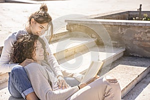 Happy young heterosexual couple smiling and reading book