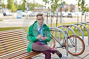 Happy young hipster man with smartphone and bike