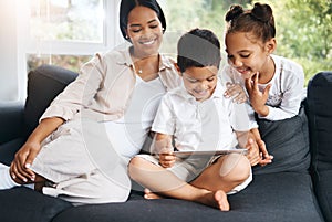 Happy young hispanic family sitting together and using tablet. Curious cute little girl and boy sitting with their