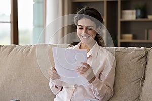 Happy young Hispanic woman reading letter with good news.