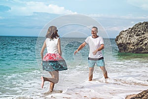 Happy young honeymoon couple having fun on the beach. Ocean, tropical vacation on Bali island, Indonesia.