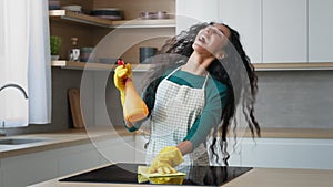 Happy young housewife arabian woman domestic cleaner maid in yellow gloves cleaning apartment washing oven by rag