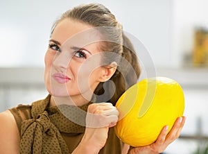 Happy young housewife checking ripeness of melon