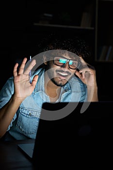 Happy young indian business man having video call meeting late at night.