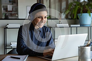 Happy young indian ethnicity female manager in headphones working remotely.