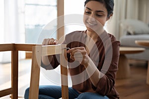 Happy young indian woman enjoy easy mounting flat pack furniture photo