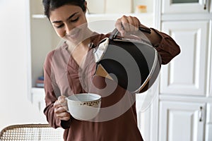 Happy young indian woman hold cup teapot brew coffee tea