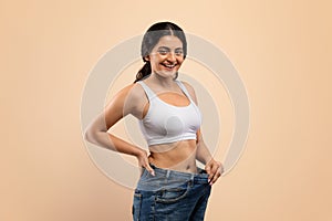 Happy Young Indian Woman Wearing Oversized Jeans Demonstrating Weight Loss Result